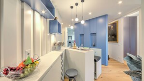 A modern kitchen with a central island, pendant lighting, and a fruit bowl on the counter. - Dandy House Few Min From Lake (Lugano)