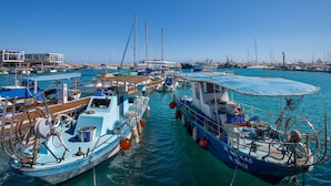A marina with various boats docked, a building with a sign, and a clear blue sky. - Sanders Only - Cute 2-bdr Apt With Balcony (Limassol)