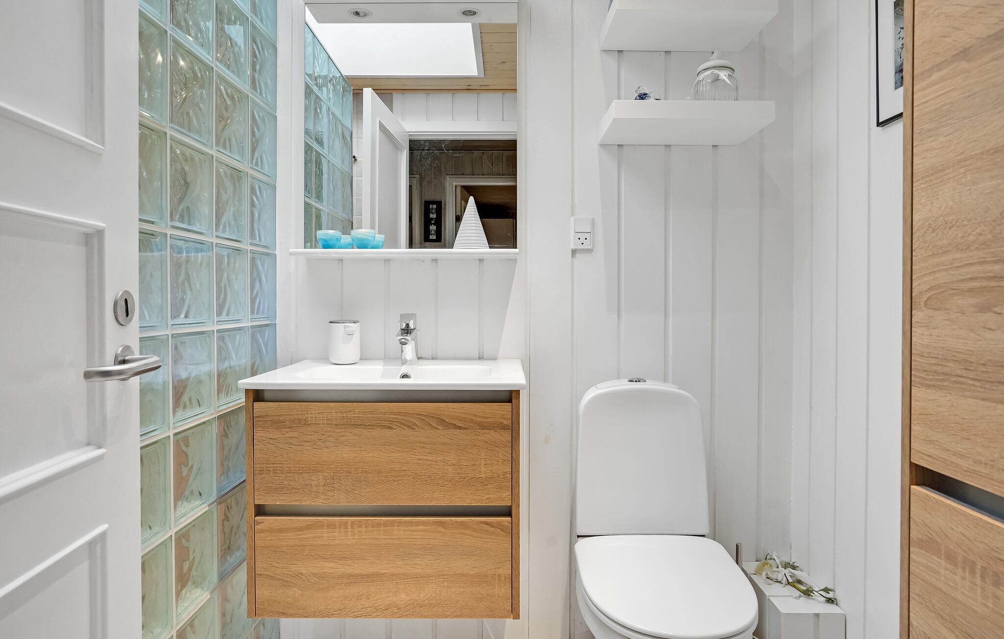 Een moderne badkamer met een wit wastafel, een houten kastje en een toilet.