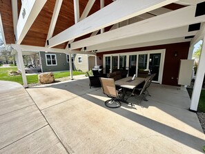 Un patio techado con una parrilla, asientos y vistas de la casa.
