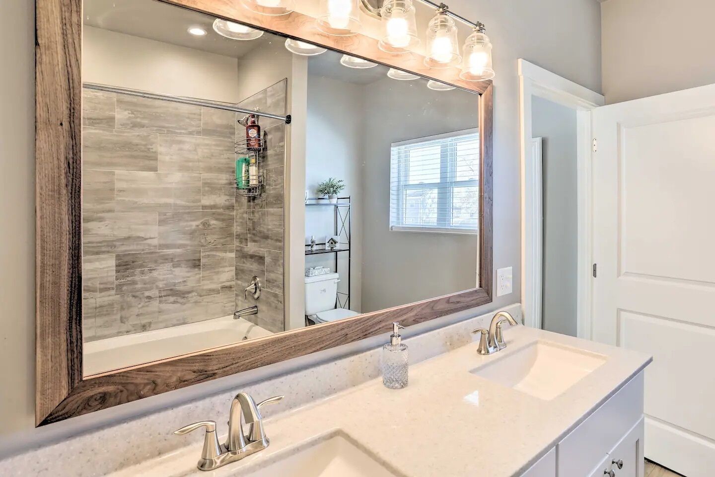 A bathroom with a large mirror, two sinks, and a shower with a glass door.