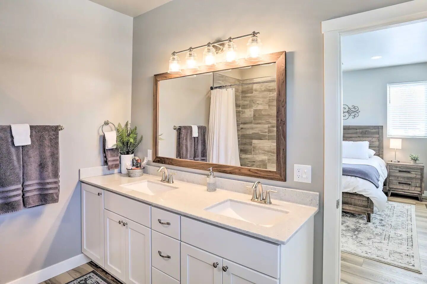 A bathroom with two sinks, a large mirror, and a shower curtain.