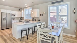 Una cocina moderna con armarios blancos, un refrigerador de acero inoxidable y una isla central con taburetes de bar.