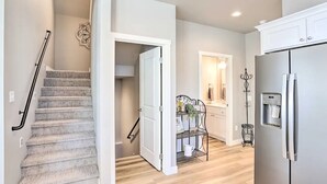 Una cocina moderna con refrigerador incorporado, un área de comedor con mesa y sillas de metal, y una escalera con barandilla.