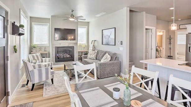 Un salón amplio con chimenea, un sof á gris, sillones a rayas y un comedor con mesa y sillas.