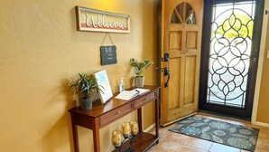 Un tavolo consolle in legno con un cartello di benvenuto, una pianta in vaso, una cornice con un'immagine e un portacandele.