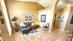 A living room with a gray sectional sofa, a wooden coffee table, and a patterned rug. There is a wall-mounted sign that reads "always welcome here." - Diving Pool, Family Friendly & Pet Friendly @Cozy Mesa home close to everything! (Mesa)