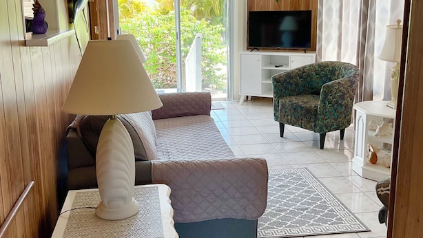 A room with a bed, a sofa, a TV, and a chair. - ISLE BE BACK To The Sunny Keys (Cudjoe Key)