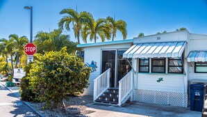 A small, single-story building with a white exterior and a blue awning. - ISLE BE BACK To The Sunny Keys (Cudjoe Key)