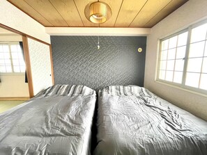 Cozy retreat with a single bed against the wall, featuring a minimalist design and a large window.