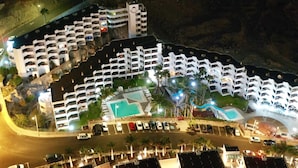 Ett hotell med flera våningar, en pool, en parkeringsplats och utsikt över det omgivande landskapet.