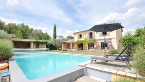 A swimming pool with a wooden deck, lounge chairs, and umbrellas. - Stunning home in Fayence with sauna (Fayence)