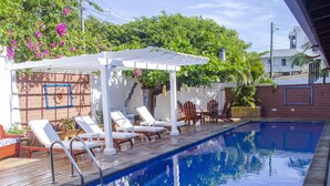 Ein Swimmingpool mit Liegestühlen und einer Pergola.