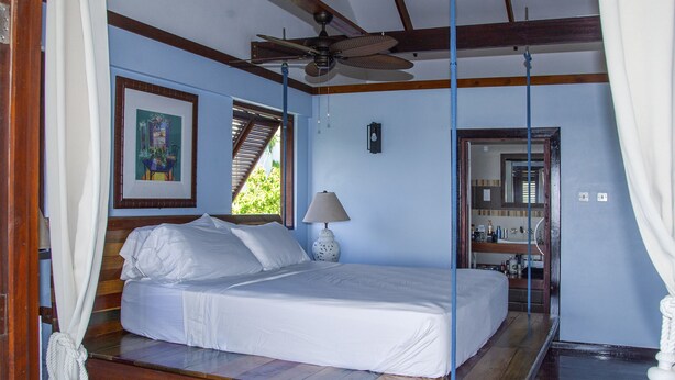 Ein Schlafzimmer mit einem Bett, einem Deckenventilator, einem Fenster und einem Bild an der Wand.