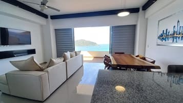 Una sala de estar moderna con un sofá, una mesa de comedor y un televisor montado en la pared.