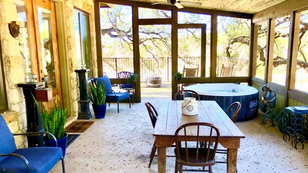 Un patio techado con mesa de madera, sillas y un jacuzzi.