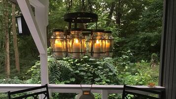 A porch with a glass railing, a hanging lantern, and a candle holder with candles.
