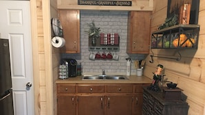 A kitchen with wooden cabinets, a brick backsplash, and a sign above the sink that reads "THANKFUL*GRATEFUL*BLESSED".