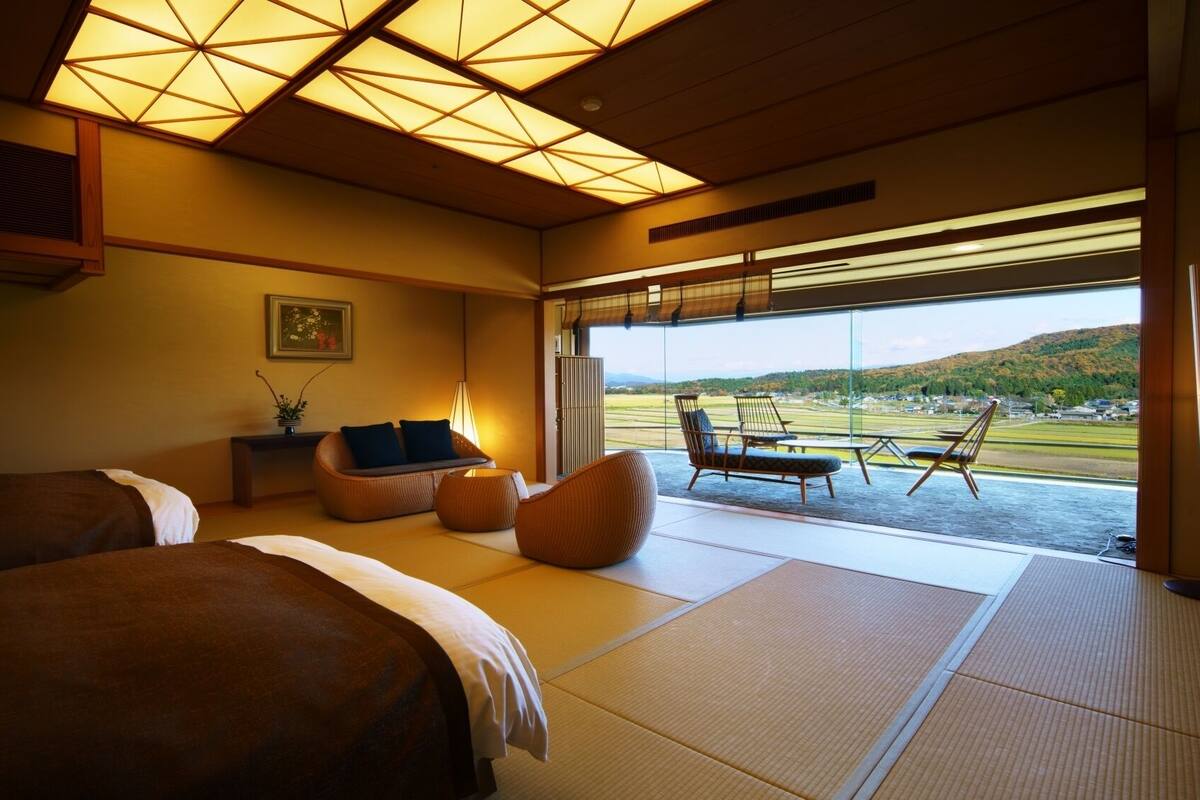 A hotel room with two beds, a seating area with a view, and a large window.