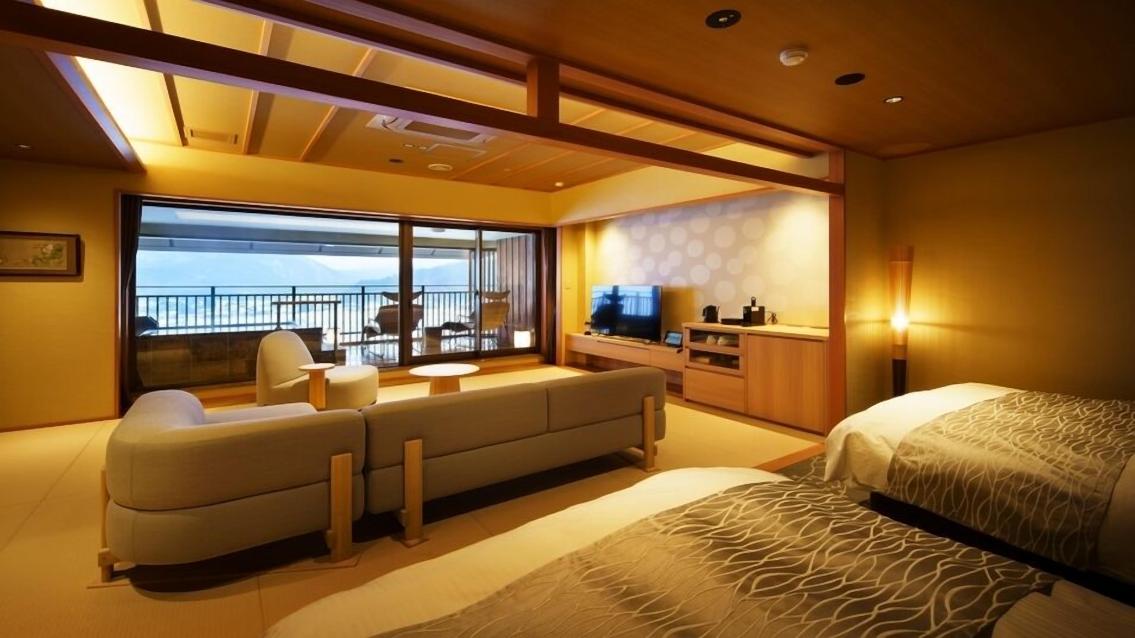 A modern hotel room with a balcony, a sofa, a bed, and a TV.