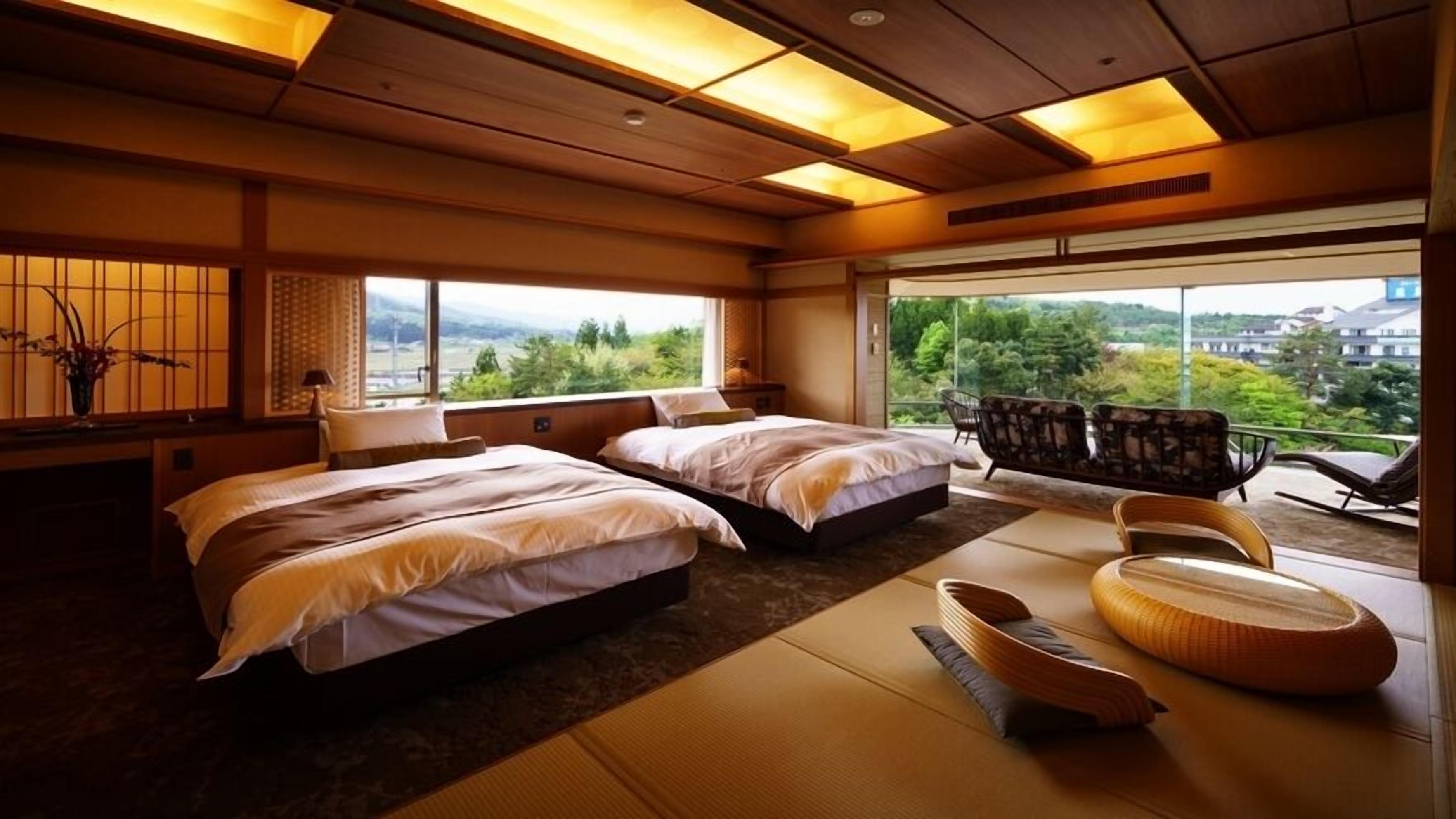 A hotel room with two beds, tatami mats, a balcony with chairs, and a view of greenery.
