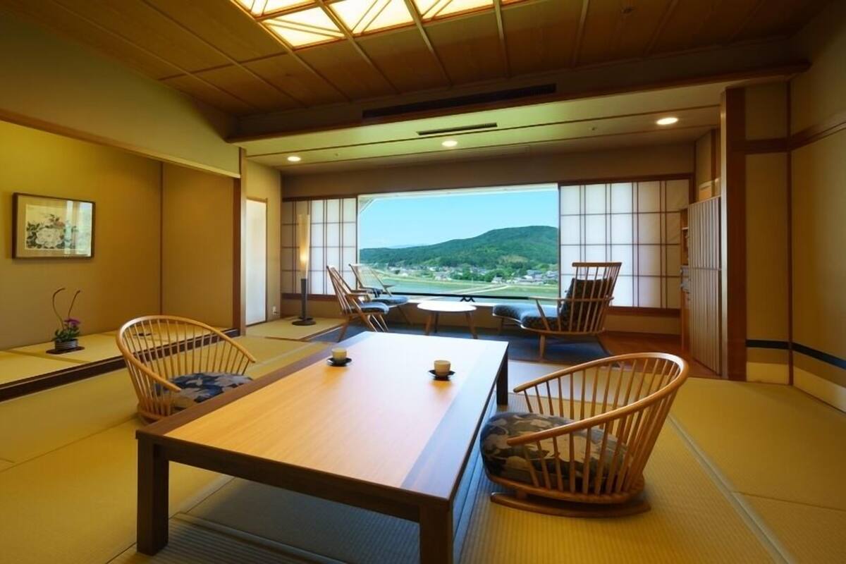 A traditional Japanese room with tatami flooring, a low table, and chairs.