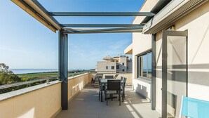 Ein Balkon mit Tisch und Stühlen, eine Bank und Meerblick.