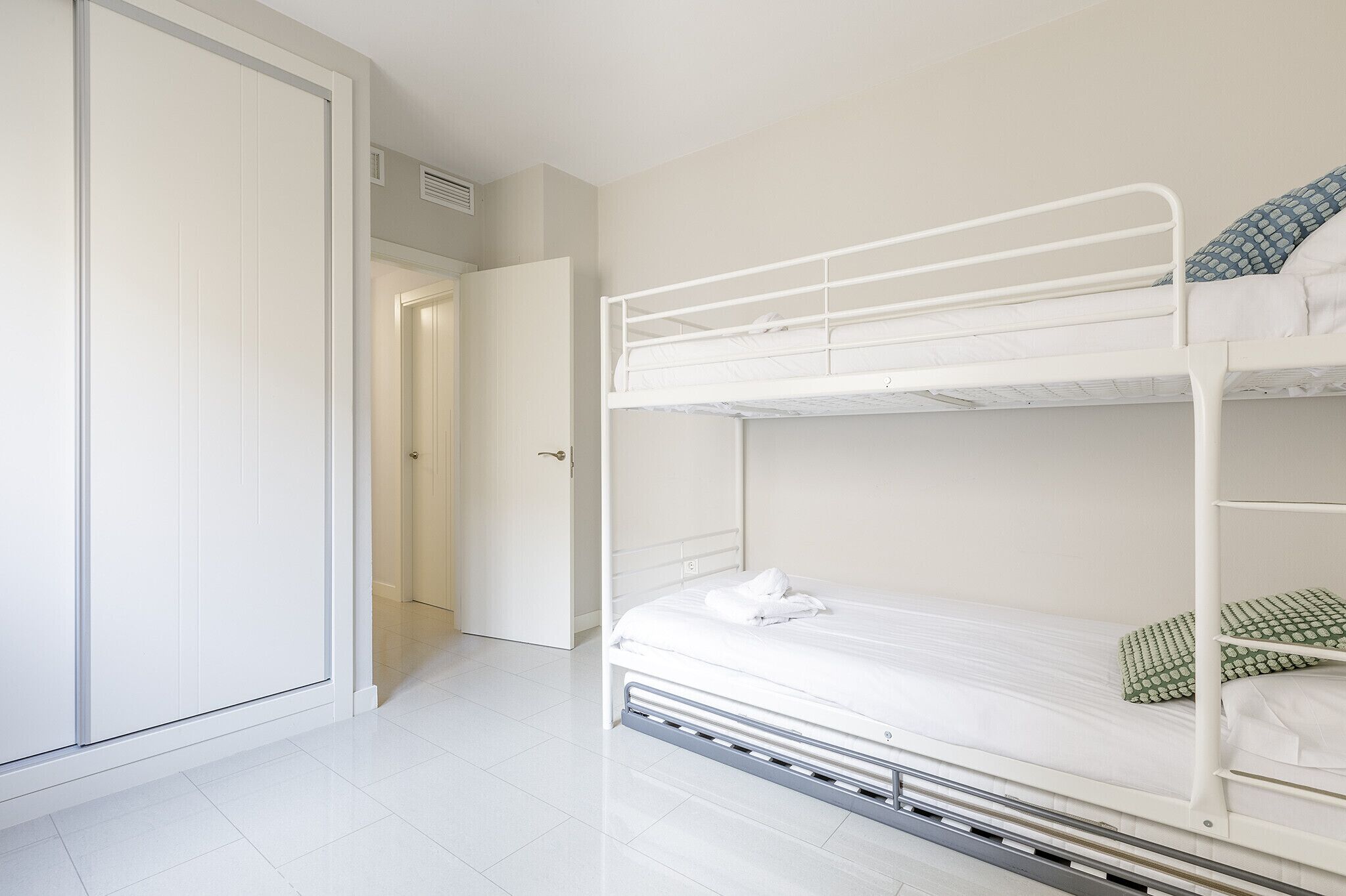 A bunk bed room with white walls and a door leading to another room.