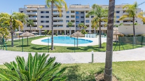 Ein Hotel mit Schwimmbecken, umgeben von Palmen und einem eingezäunten Bereich.