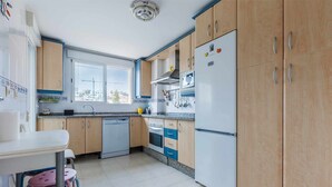 Eine Küche mit Holzschränken, einem weißen Kühlschrank und einem Fenster, das für natürliches Licht sorgt.