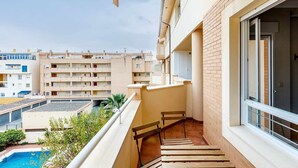 Ein Balkon mit Blick auf einen Pool und benachbarte Gebäude.