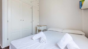 Ein Hotelzimmer mit einem ordentlich bezogenen Bett, einem kleinen Nachttisch und einem Kleiderschrank.