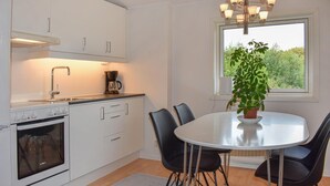 Une cuisine moderne avec des meubles blancs, une machine à café et un coin repas comprenant une table ronde et des chaises.