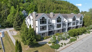 A multi-story building with a stone chimney, large windows, and balconies. - Walk to Shops! 3 Story Condo w/ Views + Elevator (Fish Creek)