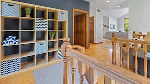 A modern interior with a wooden staircase, a built-in storage unit with patterned containers, and a living area with a sofa and a coffee table. - Walk to Shops! 3 Story Condo w/ Views + Elevator (Fish Creek)