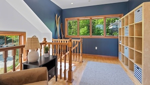 A room with a staircase, a large window, a bookshelf, and a lamp. - Walk to Shops! 3 Story Condo w/ Views + Elevator (Fish Creek)