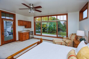A bedroom with a large window, a bed, a wooden headboard, a nightstand, and a ceiling fan. - Walk to Shops! 3 Story Condo w/ Views + Elevator (Fish Creek)