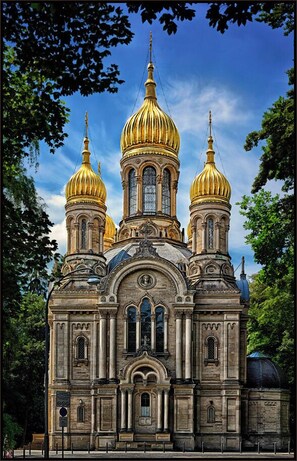 A historic building with three golden domes and a central tower.