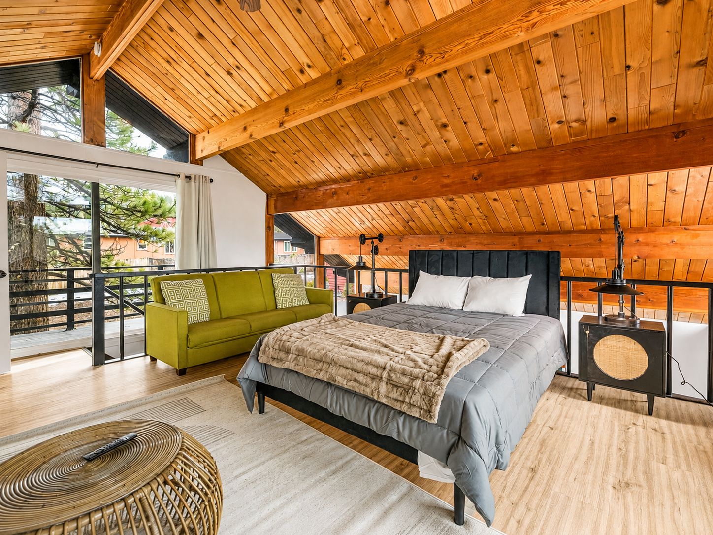 Une chambre spacieuse avec un grand lit, un canapé vert et un fauteuil en osier.