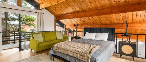 Une chambre spacieuse avec un grand lit, un canapé vert et un fauteuil en osier.