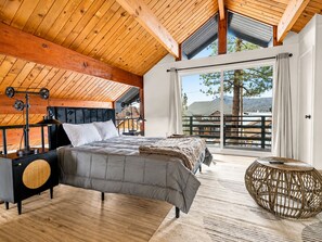 A bedroom with a bed, bedside table, and a view of the outdoors.