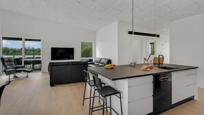 Eine moderne Küche mit einer zentralen Kochinsel, Barhocker und einem integrierten Geschirrspüler.