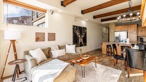 A modern living room with a sofa, coffee table, and a dining area with chairs. - Redstone Condo in Great Location, Hot Tub & Year-Round Recreation! Park City Newark 38 (Park City)