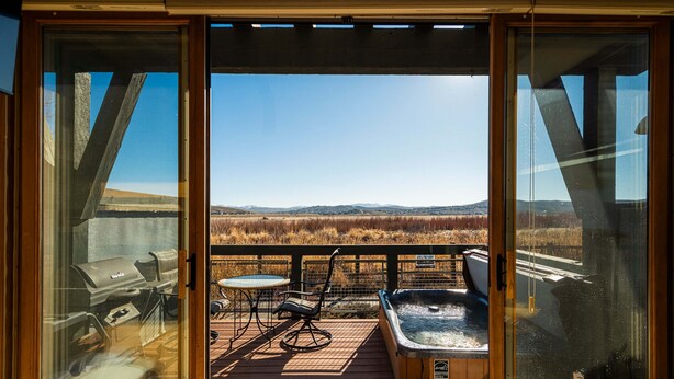 A deck with a grill, hot tub, and seating area with a view of the landscape. - Redstone Condo in Great Location, Hot Tub & Year-Round Recreation! Park City Newark 38 (Park City)
