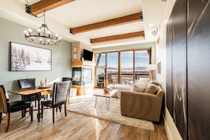Un salón amplio con una mesa de comedor de madera, asientos cómodos, una chimenea y un gran ventanal con vistas panorámicas.