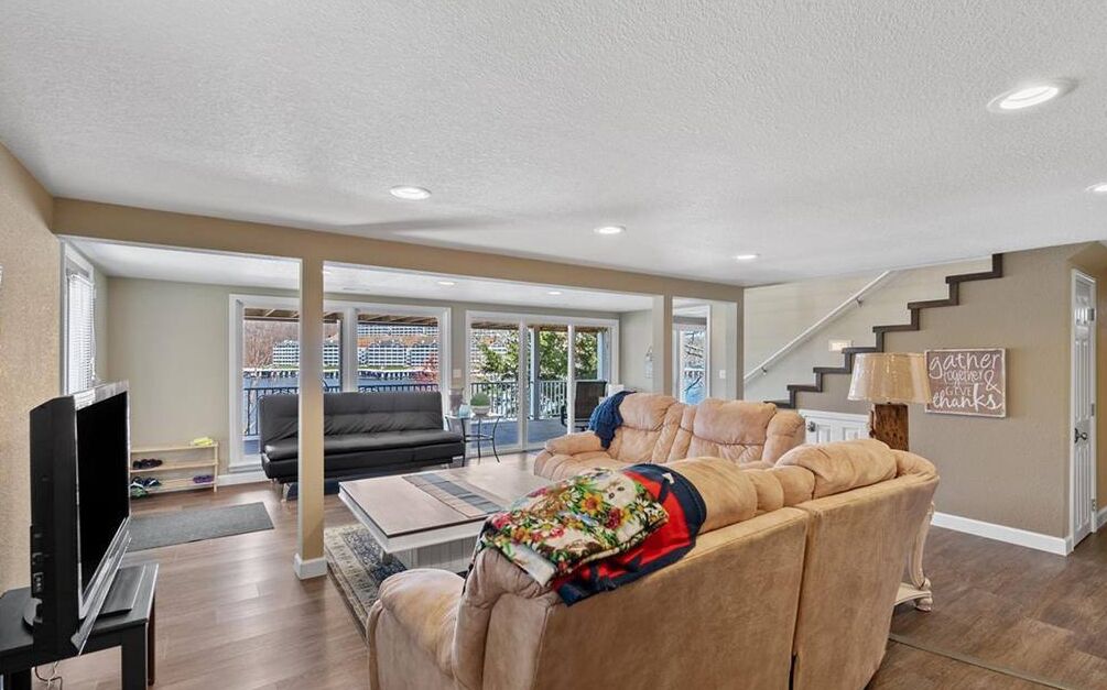 A spacious living room with a large sofa, a television, and a staircase leading to another level.