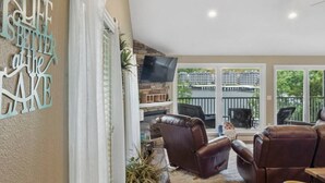 A spacious living area with leather sofas, a fireplace, and a large TV.