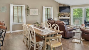A dining area with a wooden table and chairs, a fireplace, and a leather sofa.