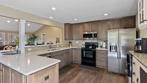 A modern kitchen with wooden cabinets, stainless steel appliances, and a large island.