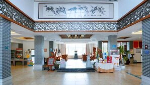 A spacious lobby with a central seating area, a reception desk, and a decorative ceiling. - China Magnetic Mountain Springs Park (Yantai)